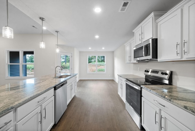 kitchen with stainless steel appliances, light stone countertops, pendant lighting, white cabinets, and sink