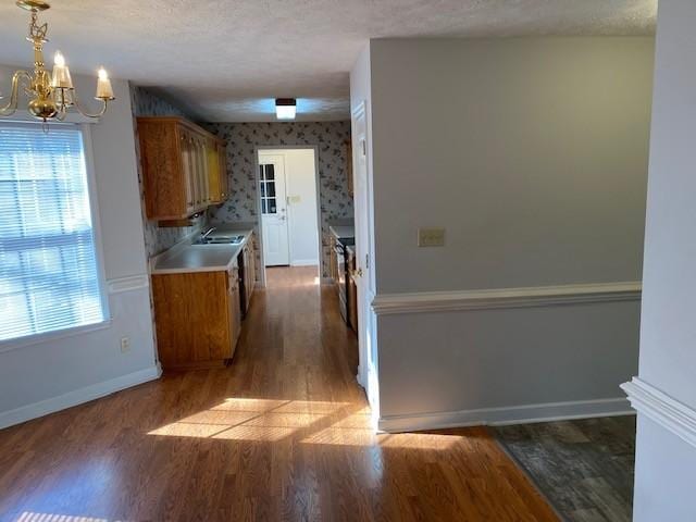 kitchen with a textured ceiling, dark wood-type flooring, a chandelier, and hanging light fixtures