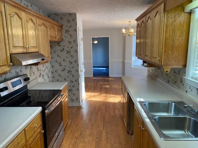 kitchen featuring stainless steel range with electric cooktop, light hardwood / wood-style floors, sink, hanging light fixtures, and a chandelier