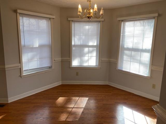 unfurnished dining area featuring a notable chandelier and dark hardwood / wood-style floors