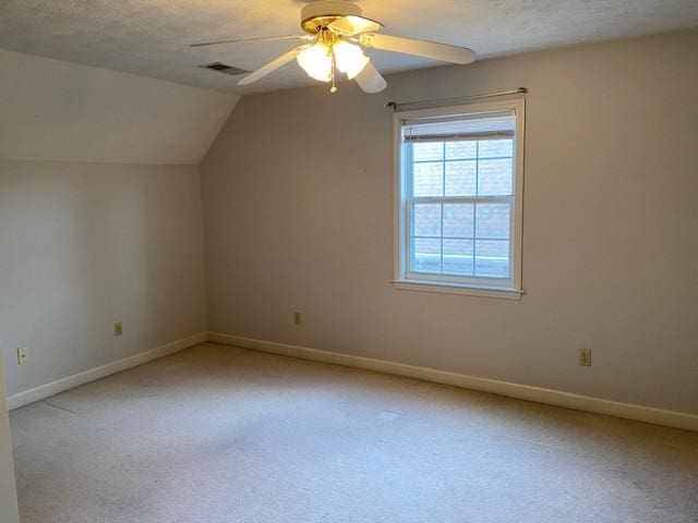 additional living space with vaulted ceiling, ceiling fan, a textured ceiling, and light carpet