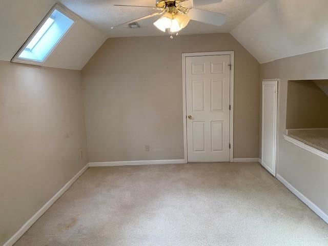 bonus room with light carpet, ceiling fan, and lofted ceiling with skylight