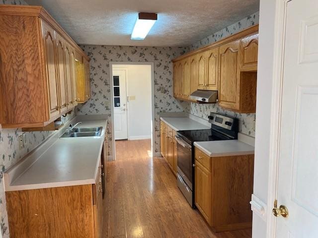 kitchen featuring electric stove, a textured ceiling, light hardwood / wood-style flooring, and sink