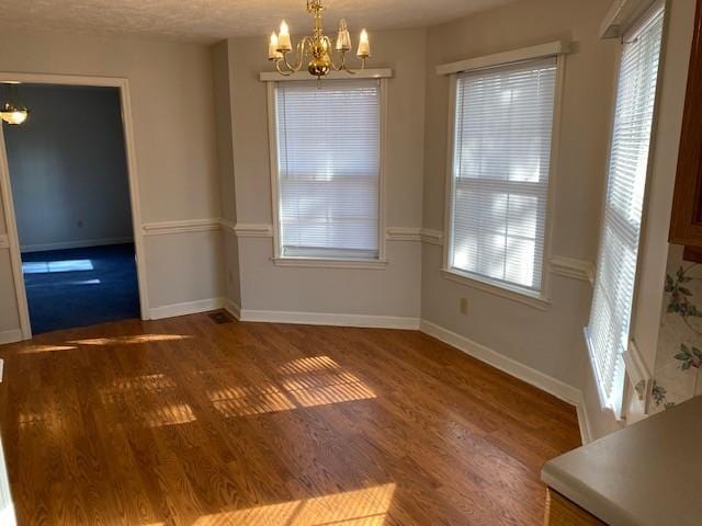 unfurnished dining area featuring dark hardwood / wood-style floors and an inviting chandelier