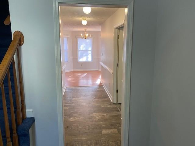 hallway featuring dark hardwood / wood-style flooring and a chandelier