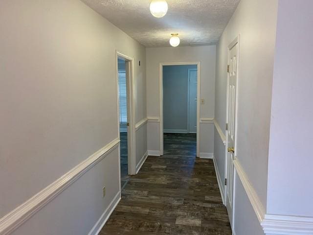 hallway with dark wood-type flooring and a textured ceiling