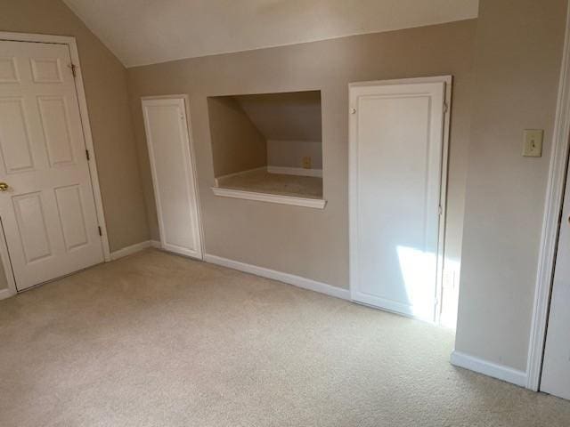 unfurnished room featuring vaulted ceiling and light carpet