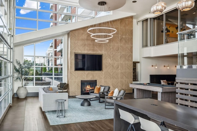 living room featuring a towering ceiling, dark hardwood / wood-style floors, wood walls, and a tiled fireplace