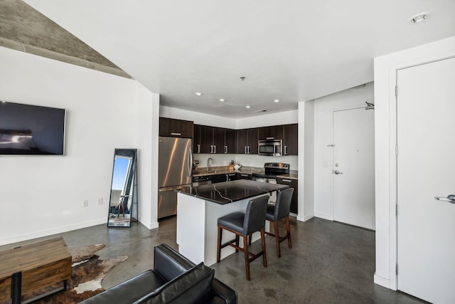 kitchen featuring a kitchen island, sink, a kitchen breakfast bar, stainless steel appliances, and dark brown cabinets