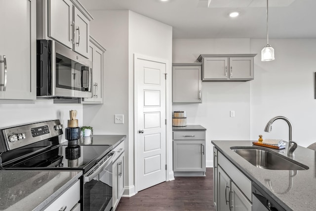 kitchen with stainless steel appliances, dark stone counters, sink, hanging light fixtures, and gray cabinetry