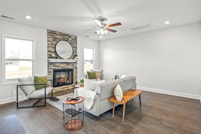 living room with ceiling fan, dark hardwood / wood-style floors, and a stone fireplace