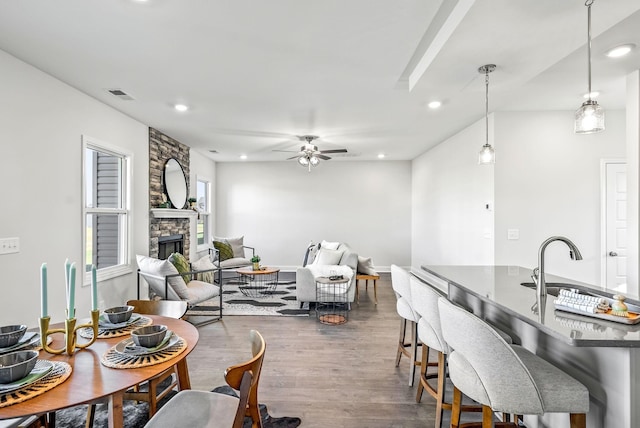 interior space with ceiling fan, dark hardwood / wood-style floors, and a stone fireplace