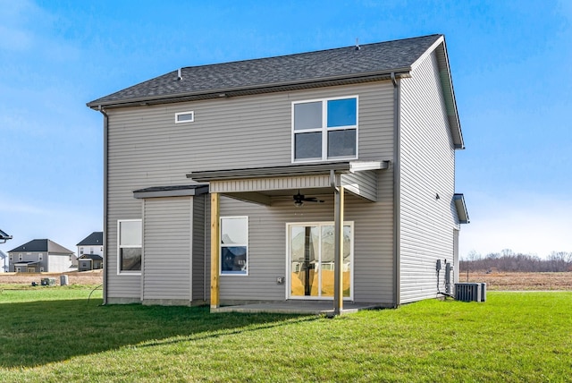 rear view of property with ceiling fan and a yard