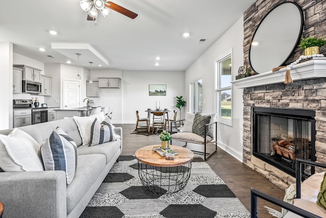 living room with ceiling fan, a fireplace, and dark hardwood / wood-style floors