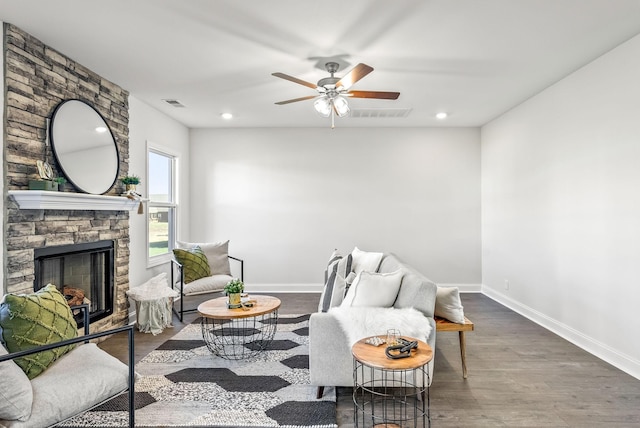 living room featuring dark wood-type flooring, ceiling fan, and a fireplace