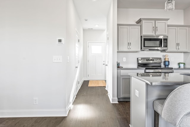 kitchen with a kitchen bar, gray cabinets, and stainless steel appliances