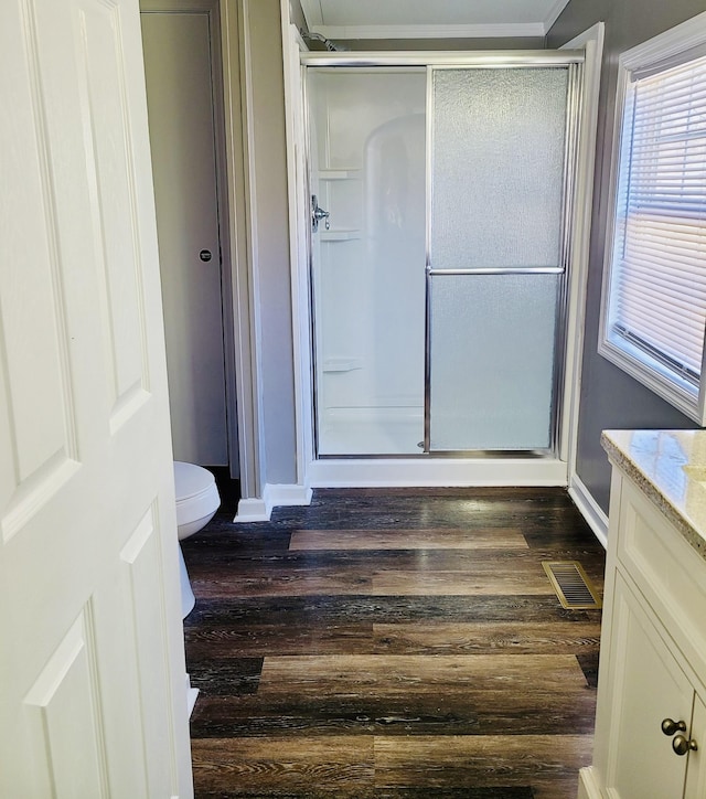 bathroom featuring toilet, a shower with shower door, hardwood / wood-style floors, and vanity