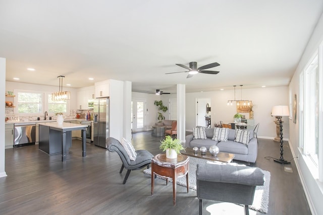 living room with sink, ceiling fan with notable chandelier, and dark wood-type flooring