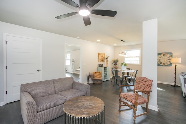 living room featuring dark wood-type flooring and ceiling fan with notable chandelier