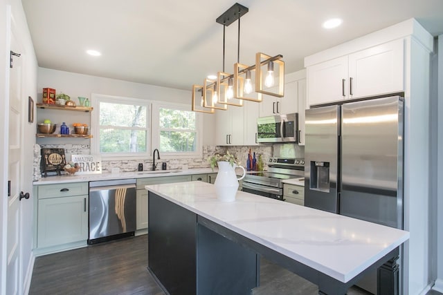 kitchen featuring pendant lighting, sink, white cabinetry, stainless steel appliances, and light stone counters