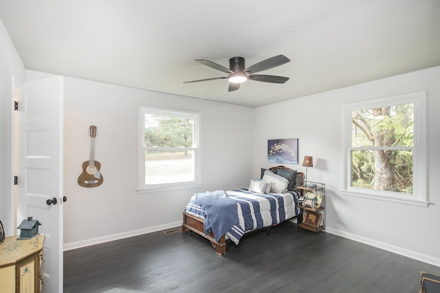 bedroom featuring ceiling fan, dark hardwood / wood-style flooring, and multiple windows