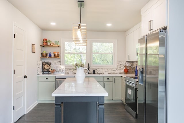 kitchen featuring appliances with stainless steel finishes, hanging light fixtures, a center island, light stone countertops, and decorative backsplash