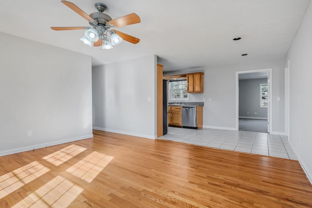 unfurnished living room with ceiling fan, sink, and light wood-type flooring