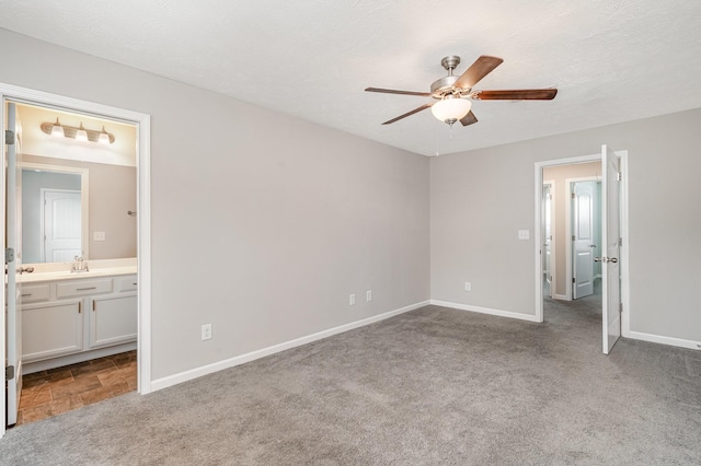 unfurnished bedroom with sink, ensuite bath, light colored carpet, a textured ceiling, and ceiling fan