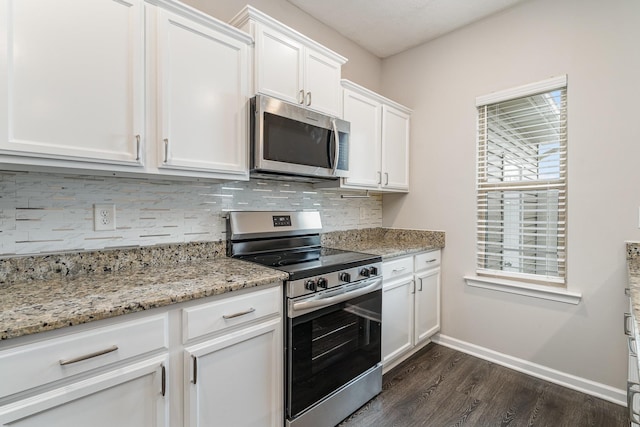 kitchen with dark wood-type flooring, white cabinetry, light stone counters, appliances with stainless steel finishes, and backsplash