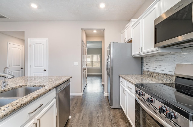 kitchen with appliances with stainless steel finishes, sink, white cabinets, and light stone counters