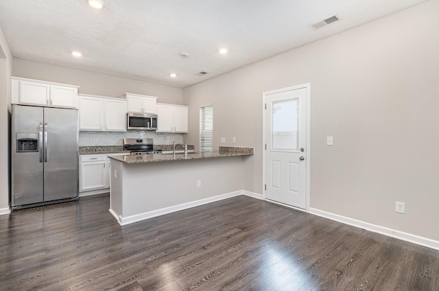 kitchen with dark hardwood / wood-style floors, sink, white cabinets, dark stone counters, and stainless steel appliances