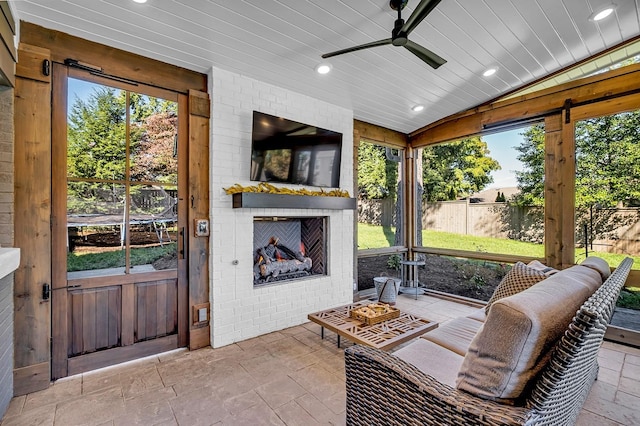 sunroom featuring lofted ceiling, ceiling fan, wood ceiling, and an outdoor brick fireplace