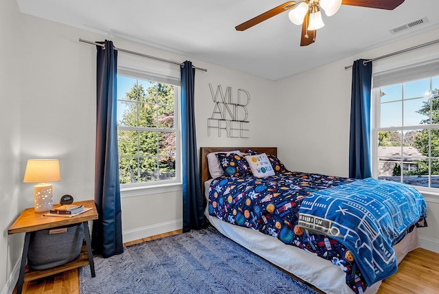 bedroom with ceiling fan, multiple windows, and hardwood / wood-style flooring