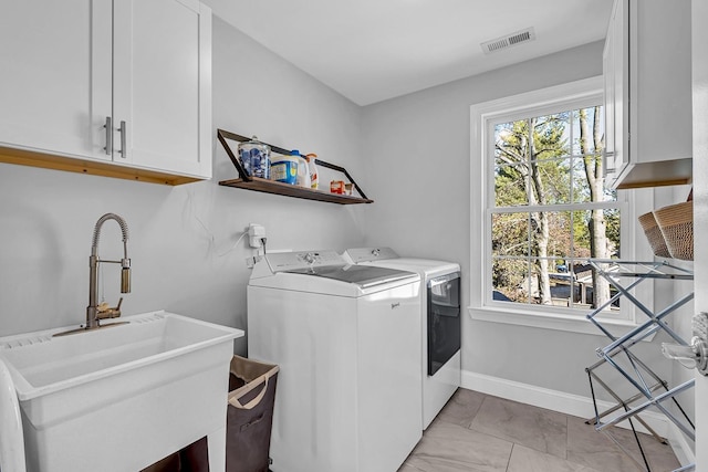 clothes washing area with cabinets, sink, and washing machine and dryer