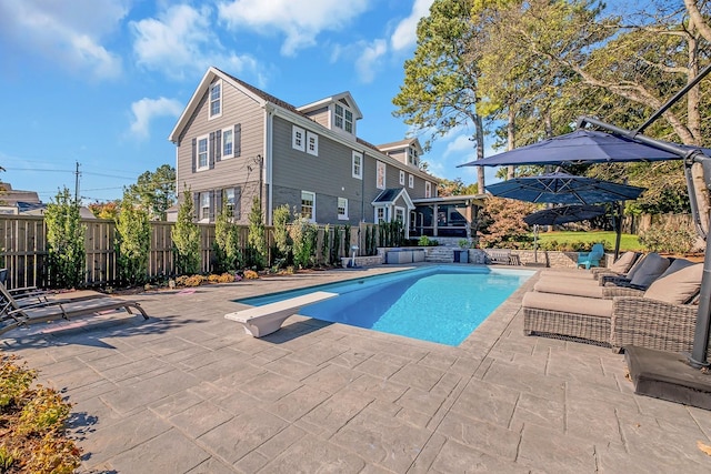 view of swimming pool with a diving board, outdoor lounge area, and a patio