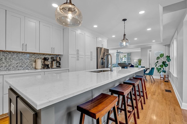 kitchen with white cabinets, stainless steel fridge with ice dispenser, and an island with sink