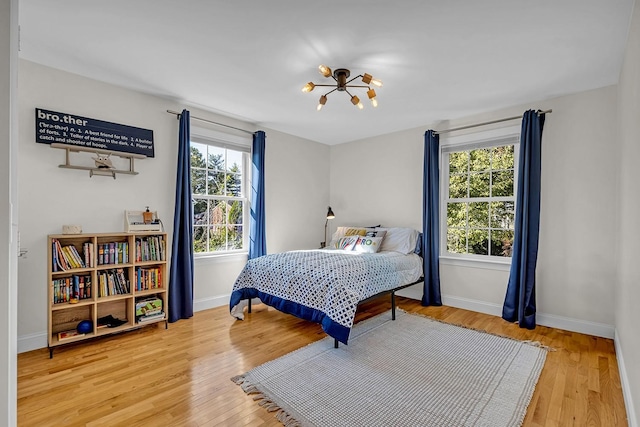 bedroom with hardwood / wood-style floors and a notable chandelier