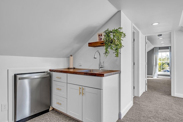 kitchen featuring vaulted ceiling, wooden counters, dishwasher, sink, and light carpet