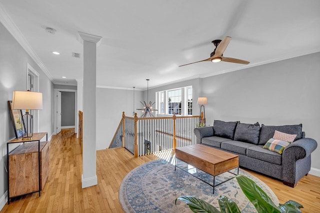 living room featuring ceiling fan, decorative columns, ornamental molding, and light wood-type flooring