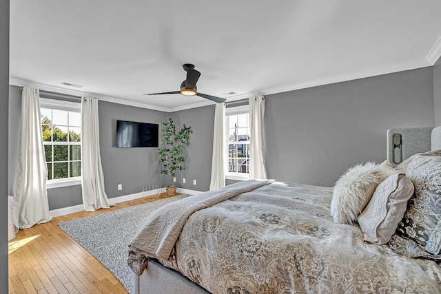 bedroom featuring ceiling fan, crown molding, wood-type flooring, and multiple windows