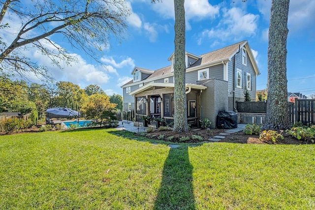 rear view of house featuring a pool, a sunroom, and a lawn