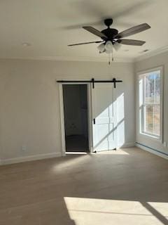 spare room with ceiling fan, crown molding, and a barn door