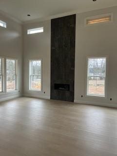 unfurnished living room featuring a healthy amount of sunlight, light wood-type flooring, and a large fireplace