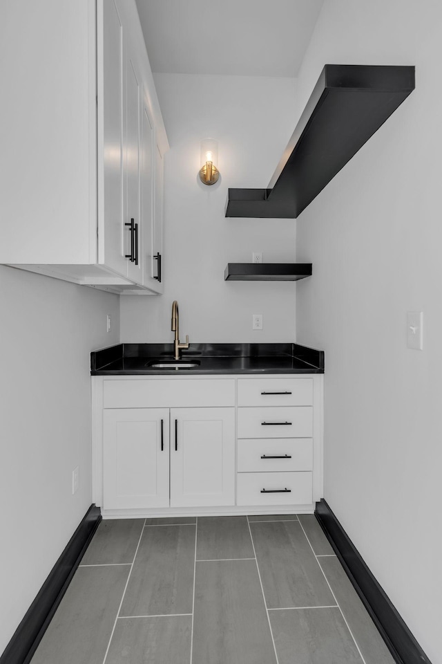 bar with sink, tile patterned floors, and white cabinets