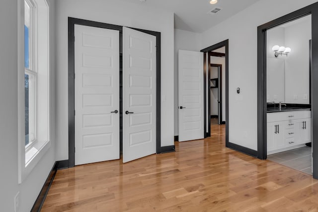 unfurnished bedroom featuring sink and light hardwood / wood-style floors