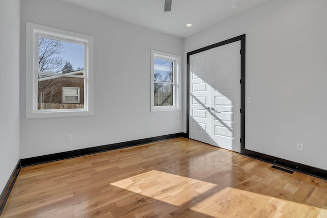 empty room with ceiling fan and light hardwood / wood-style flooring