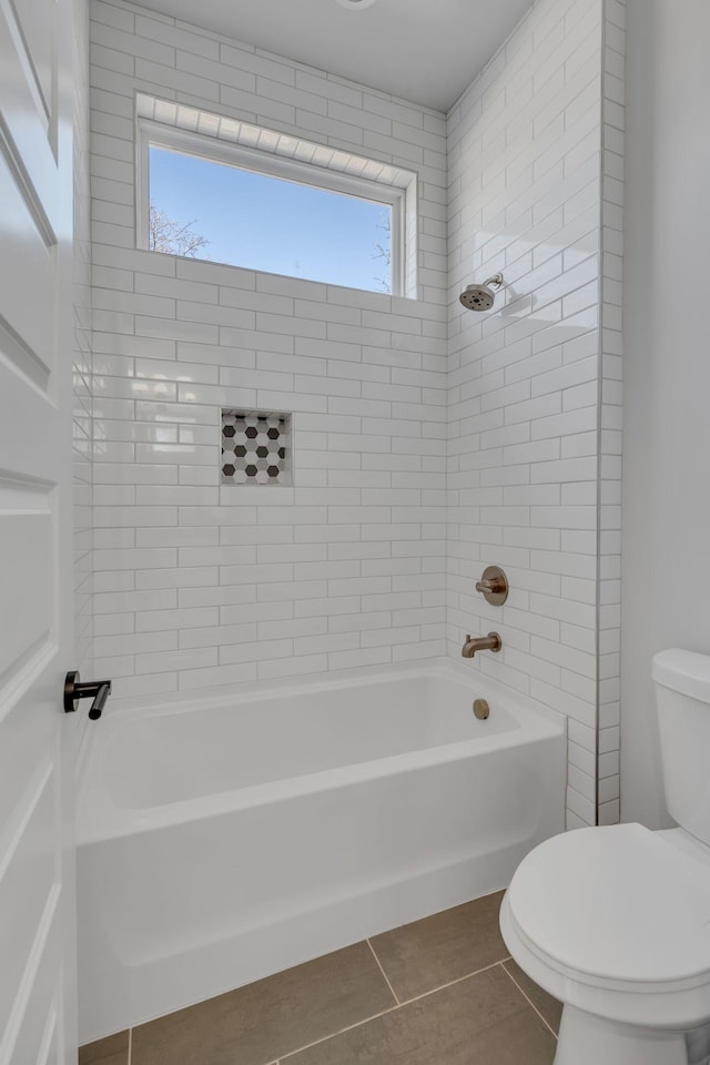 bathroom with toilet, tiled shower / bath, and a healthy amount of sunlight