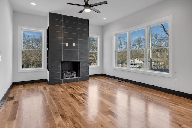 unfurnished living room with ceiling fan, a tile fireplace, and light hardwood / wood-style flooring