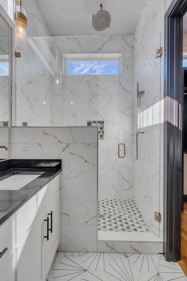 bathroom with a shower with shower door, a wealth of natural light, vanity, and tile patterned flooring