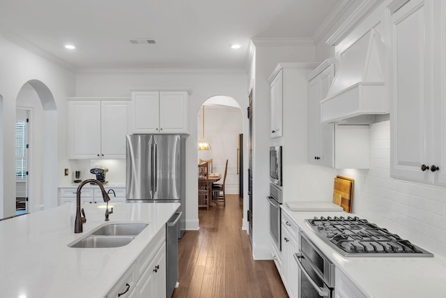 kitchen with stainless steel appliances, custom exhaust hood, white cabinets, and sink